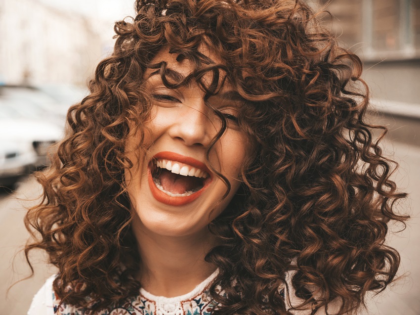 Portrait of beautiful smiling model with afro curls hairstyle.Sexy carefree girl posing in the street background.Trendy  and funny woman shows positive emotions